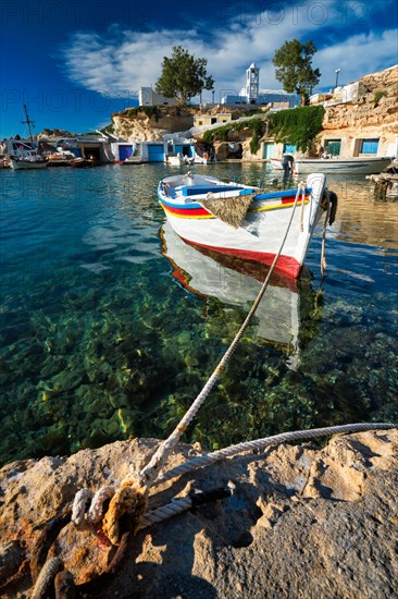 Fishing boats moored in crystal clear turquoise sea water in harbour in Greek fishing village of Mandrakia