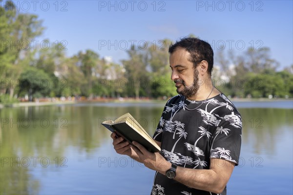 Mature man reading by a lake