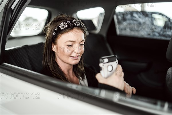 A taxi or Uber passenger talking through the phone on the car back seat