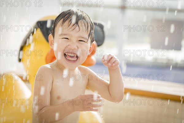 mixed-race boy having fun at the water park with large rubber duck in the background