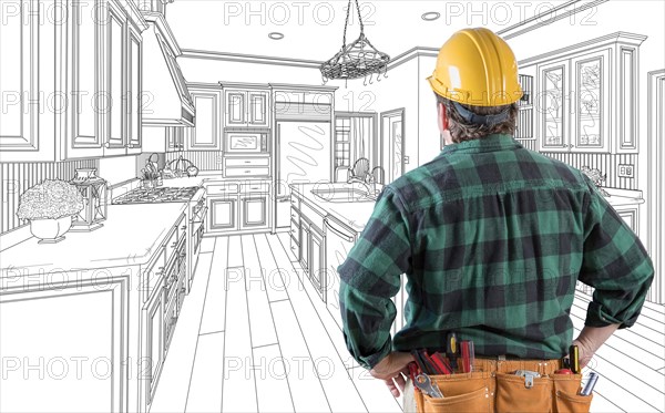 Male contractor with hard hat and tool belt looking at custom kitchen drawing on white