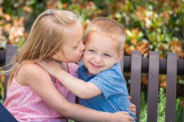 Young sister and brother having fun on the bench at the park