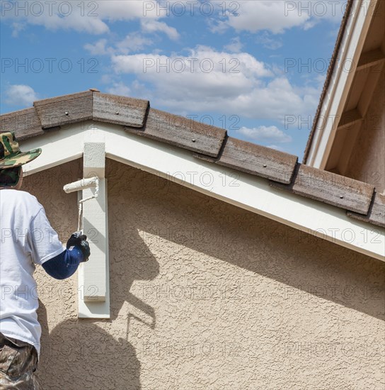 Abstract of professional painter using A roller to paint house details