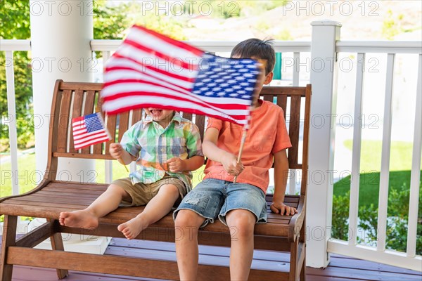 Young mixed-race chinese and caucasian brothers playing with american flags