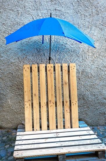Seat made of old wooden pallets with blue umbrella