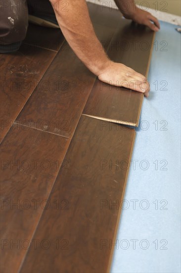 Man installing new laminate wood flooring abstract