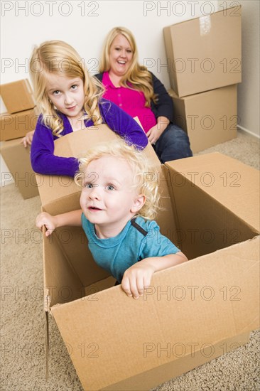 Playful young family in empty room playing with moving boxes