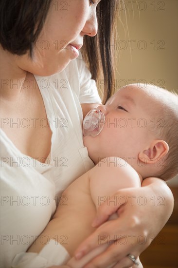 mixed-race chinese and caucasian baby boy being held by his mother