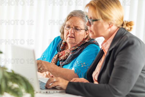 Woman helping senior adult lady on laptop computer