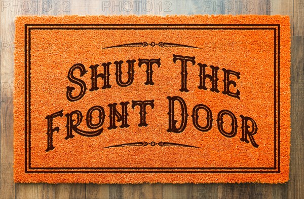 Shut the front door halloween orange welcome mat on wood floor background