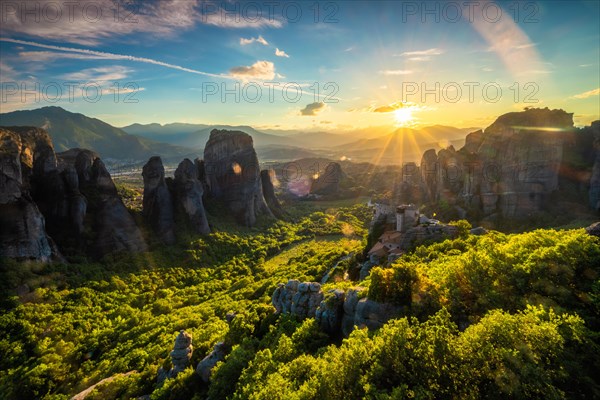 Sunset over monastery of Rousanou and Monastery of St. Nicholas Anapavsa in famous greek tourist destination Meteora in Greece on sunset with sun rays and lens flare