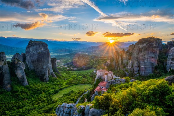 Sunset over monastery of Rousanou and Monastery of St. Nicholas Anapavsa in famous greek tourist destination Meteora in Greece on sunset with sun rays and lens flare