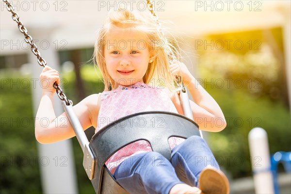 Pretty young girl having fun on the swings at the playground