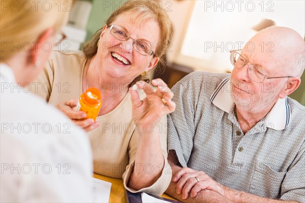 Doctor or nurse explaining prescription medicine to senior adult couple
