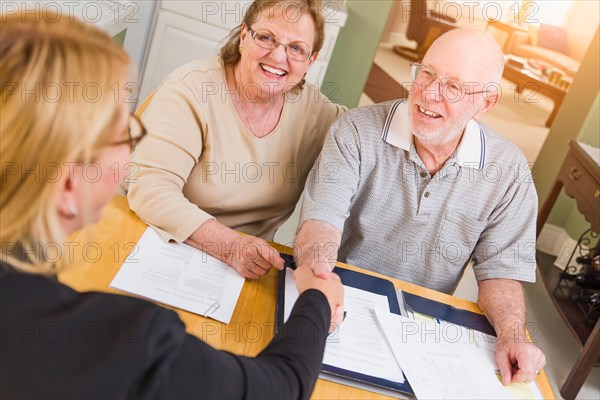 Senior adult couple going over documents in their home with agent at signing