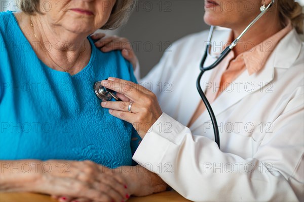 Female doctor checking the heart with stethoscope of senior adult woman