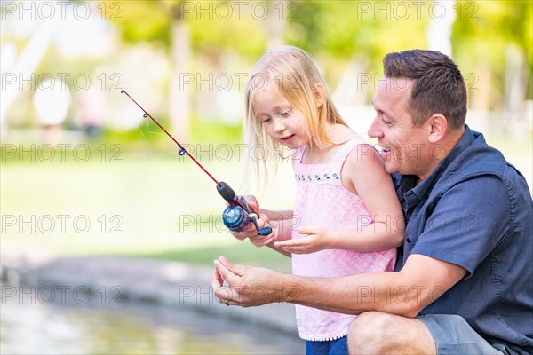 Young caucasian father and daughter having fun fishing at the lake