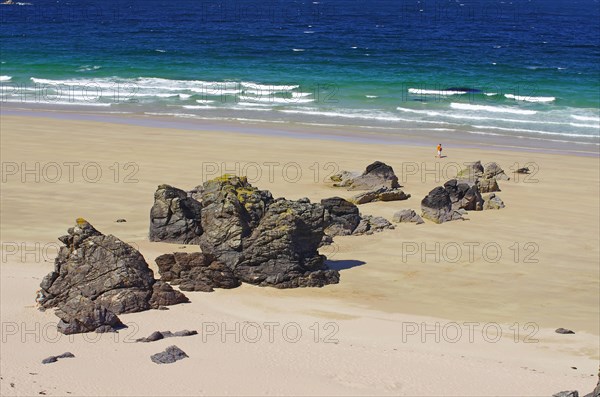 Langer Sandstrand mit einzelnen Felsen und Klippen