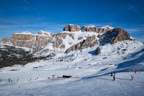 View of a ski resort piste with people skiing in Dolomites in Italy