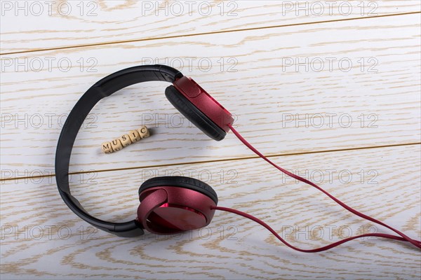 Dice-sized alphabet cubes spelling music and red headphones on wooden background