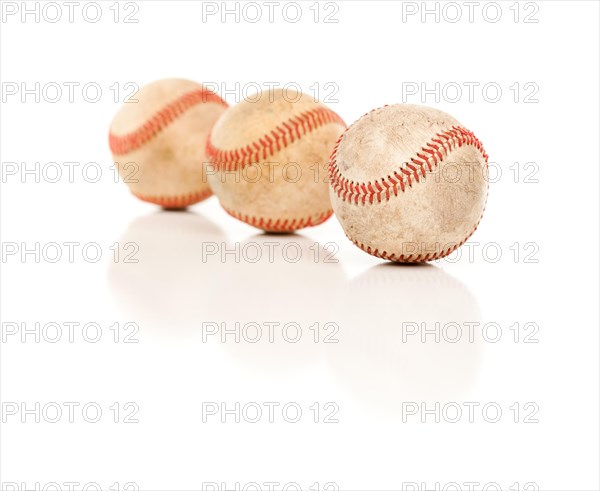 Three baseballs isolated on a reflective white background