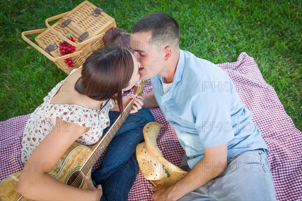 Young couple with guitar kissing in the park