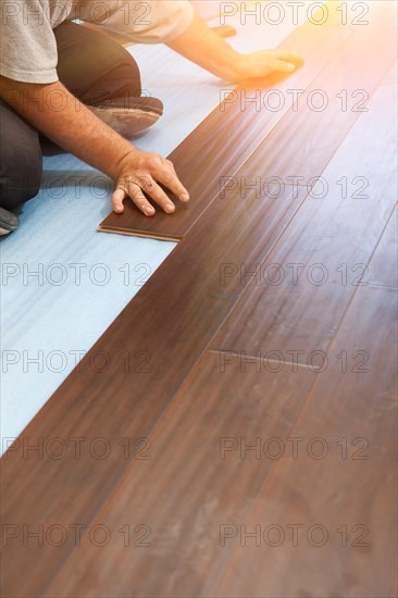 Man installing new laminate wood flooring abstract