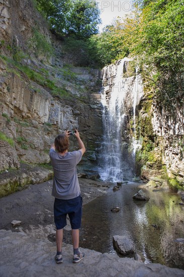 Junger Mann fotografiert die Sulphur Wasserfall bei den Schwefelbaeder in Abanotubani