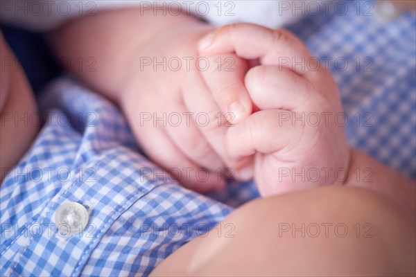 Close-up of infant hands while laying on lap of mother