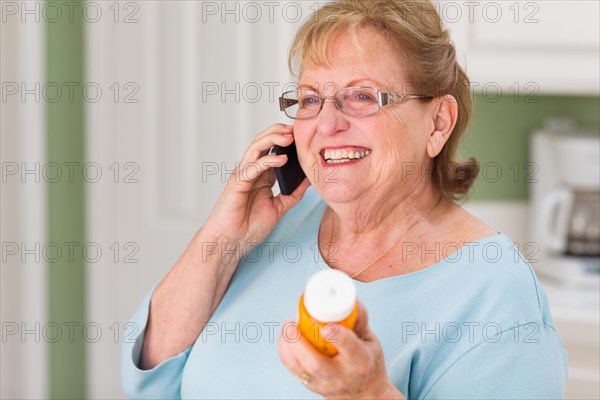 Senior adult woman on cell phone holding prescription bottle