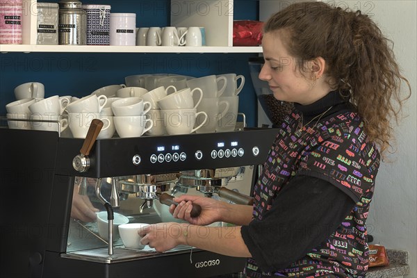 Junge Frau bereitet Kaffee an einer Espressomaschine in einem Cafe