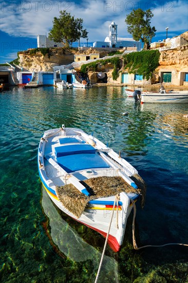 Fishing boat moored in crystal clear turquoise sea water in harbour in Greek fishing village of Mandrakia