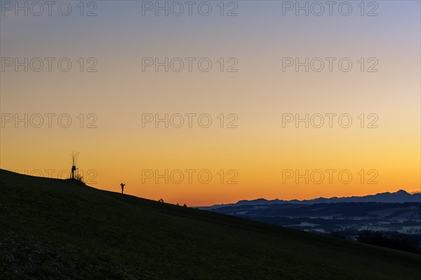 Handyfotograf bei Sonnenaufgang auf Bergruecken