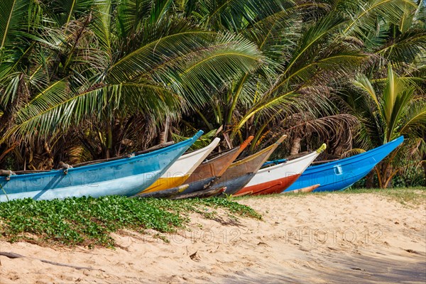 Tropical beach with row of fishing boats on sand