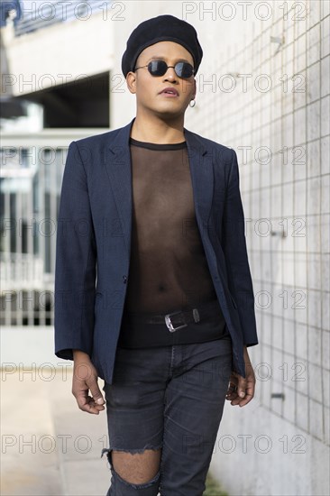 Latin gay male with makeup wearing fashion hat doing catwalk in the street