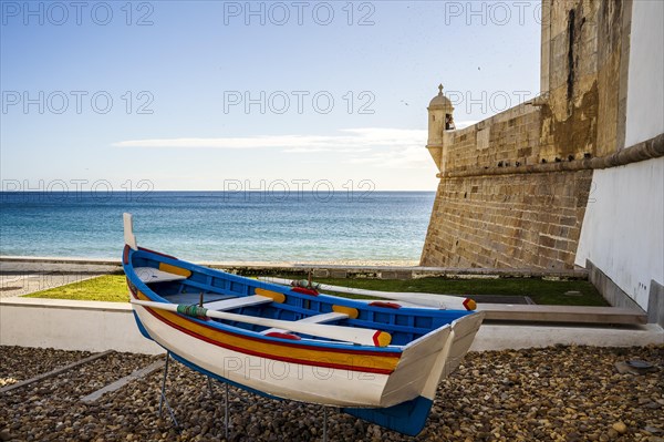 The wooden traditional boat and Saint James Fortress on the beach of Sesimbra