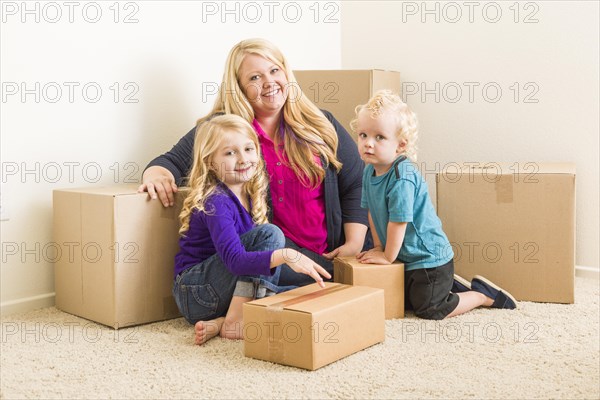 Happy young family in empty room with moving boxes