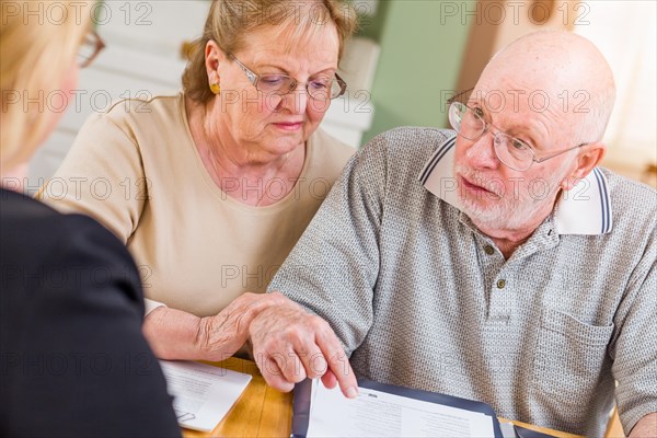 Senior adult couple going over documents in their home with agent at signing