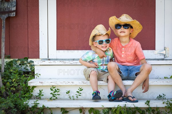 mixed-race chinese and caucasian young brothers having fun wearing sunglasses and cowboy hats