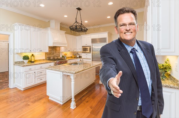 Smiling male agent reaching for hand shake in beautiful new kitchen