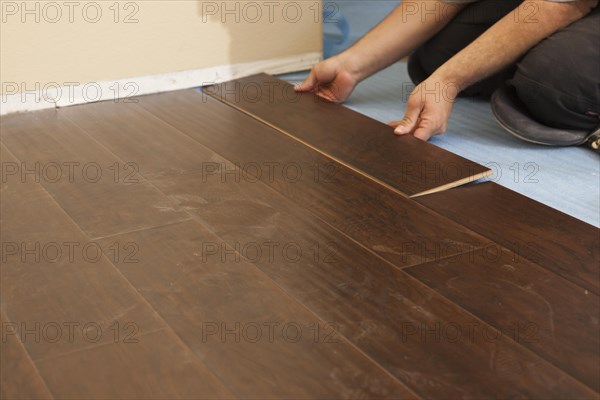 Man installing new laminate wood flooring abstract