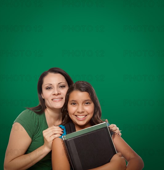 Blank chalk board behind proud hispanic mother and daughter student