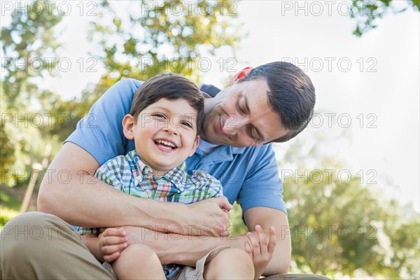 Loving young father tickling son in the park