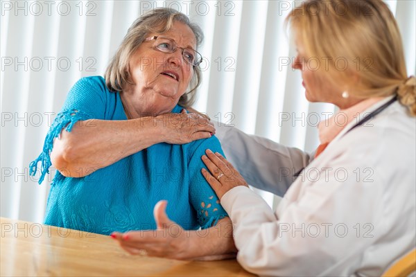 Senior adult woman talking with female doctor about sore shoulder