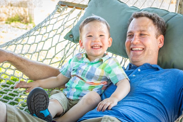 Caucasian father relaxing in hammock with mixed-race chinese son