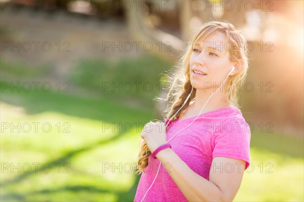 Young fit adult woman outdoors during workout listening to music with earphones