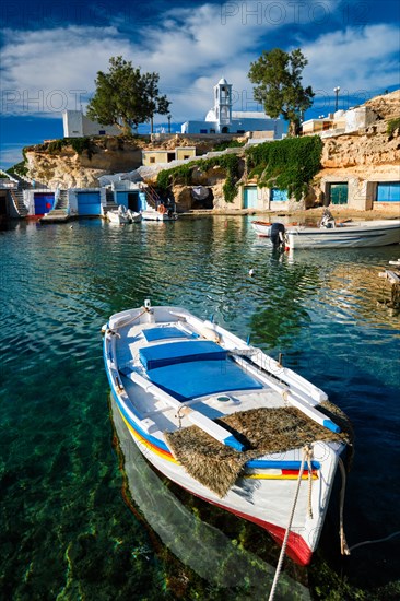 Fishing boats moored in crystal clear turquoise sea water in harbour in Greek fishing village of Mandrakia