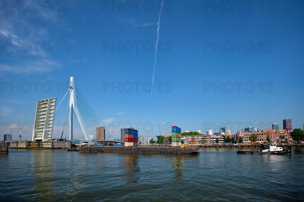 Tug boat towing barge with containers under open bascule part of Erasmusbrug bridge in Nieuwe Maas river. Rotterdam