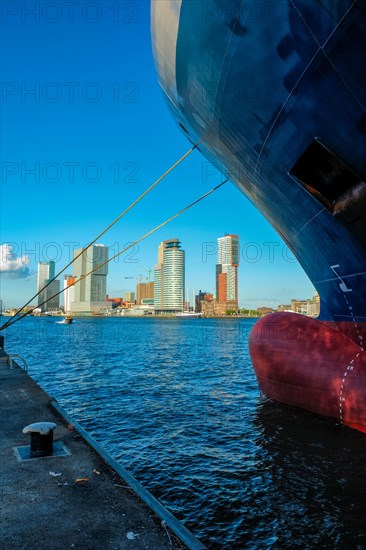 View of Rotterdam skyscrapers skyline from under cargo vessel moored to the quay of Nieuwe Maas river. Rotterdam