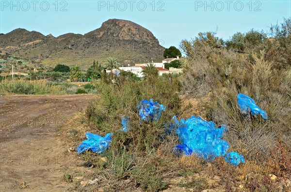 Blue crumpled plastic tarp at the edge of a field